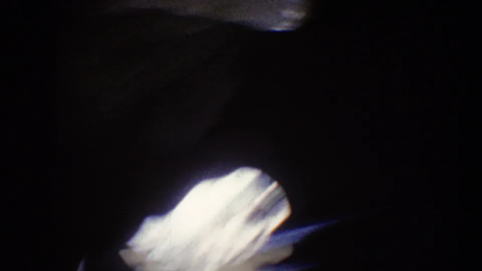 1962 Disneyland home-movie frame showing a dark passage with a bright white blur and indistinct shadowed forms.