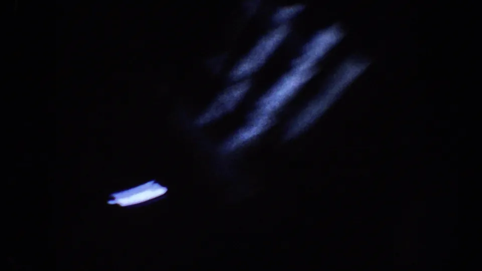 Dark 8mm Disneyland frame with blue-white motion streaks and a small bright light mark near the bottom edge.