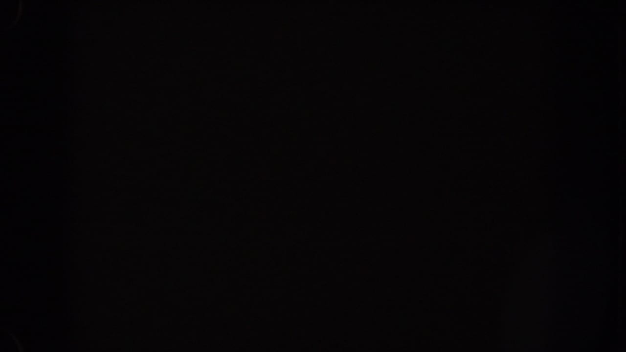 1962 Disneyland home-movie frame showing mostly black night exposure with small blue-white light flares near the upper right.