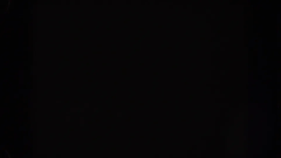 1962 Disneyland home-movie frame showing mostly black night exposure with small blue-white light flares near the upper right.
