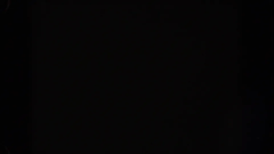 1962 Disneyland home-movie frame with a broad white flare breaking through the dark, underexposed night scene.