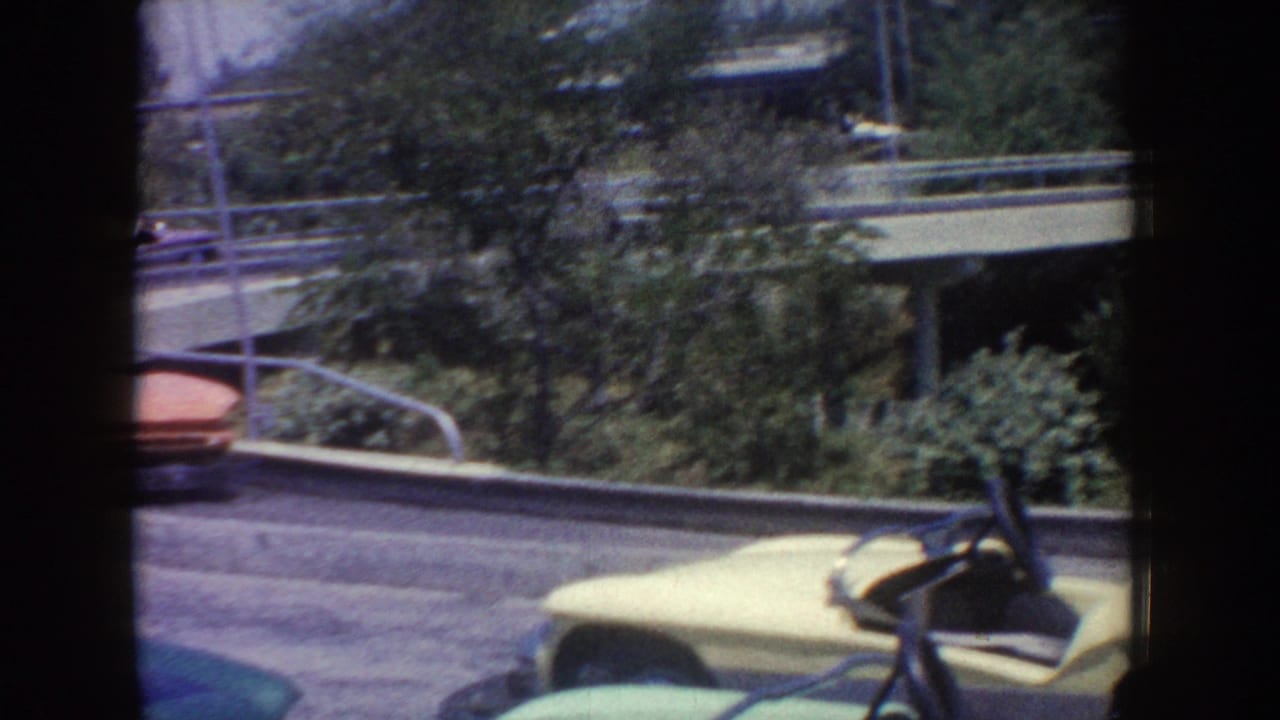 Yellow and red ride cars on a curved track beside trees and railings.