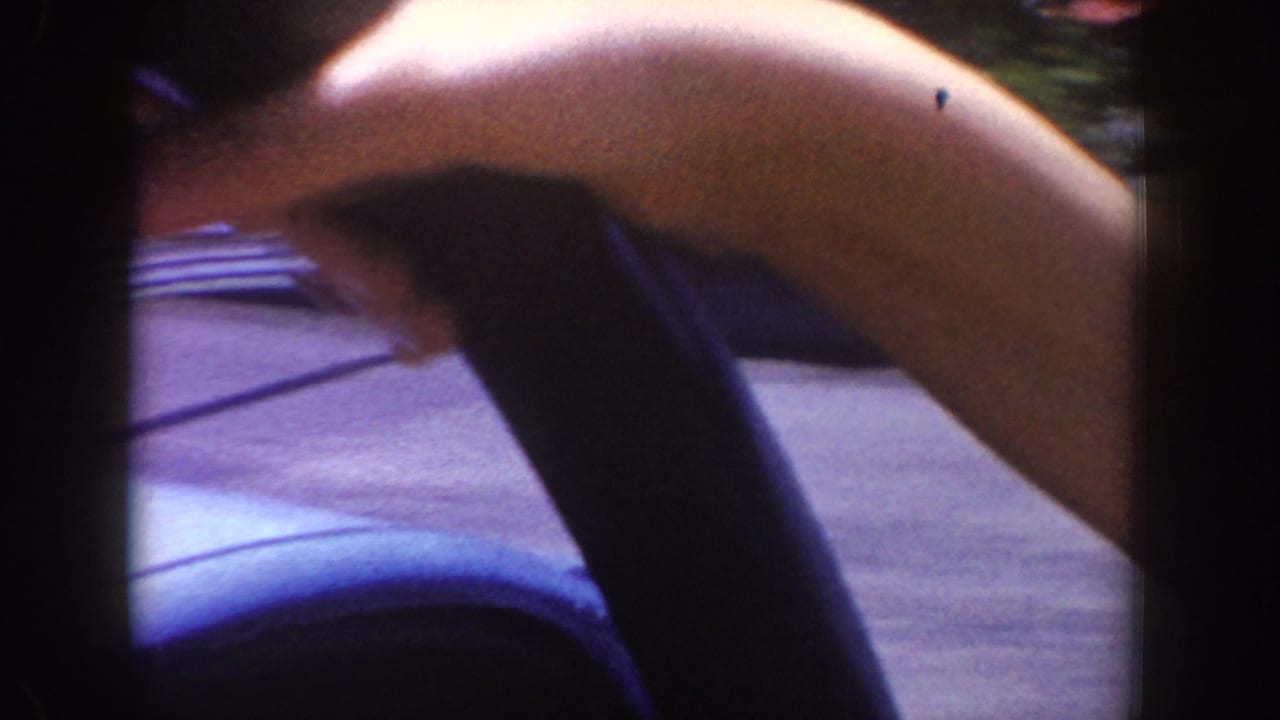 Close view of a passenger arm over a dark car door beside a paved ride roadway.