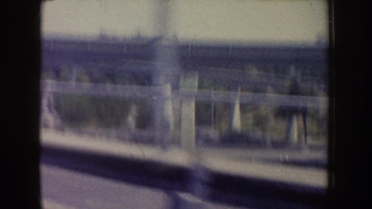 Soft 8mm view at Disneyland in 1962 showing a station-like structure or platform glimpsed from a moving vehicle window.