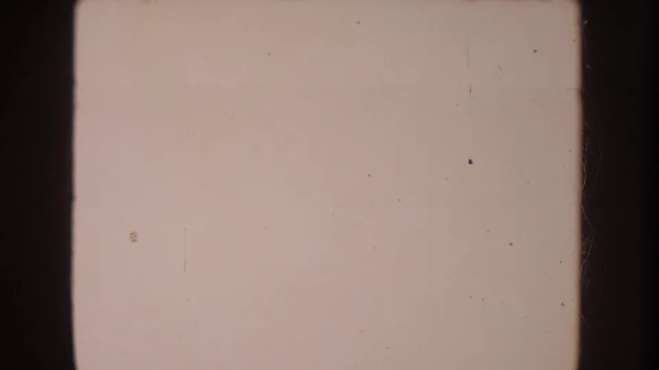 Pale 8mm frame from the 1962 clip with little visible subject detail, showing dust, scratches, and dark film borders.