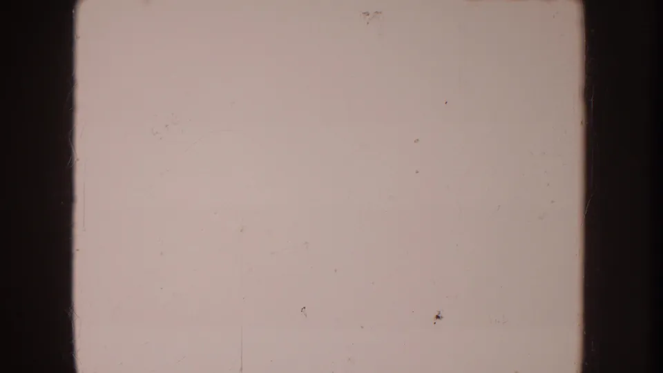 A near-blank 8mm home-movie frame with faded pink tone, surface marks, and visible film border rather than clear subject detail.