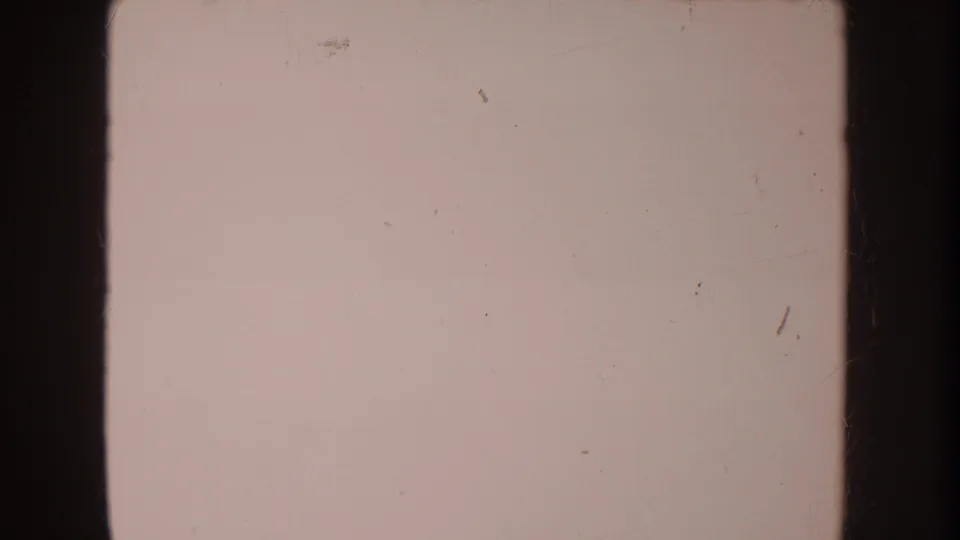 Soft 8mm frame from the 1962 Disneyland home-movie clip, mostly showing a pale blanket or sheet with film borders, grain, and scratches.