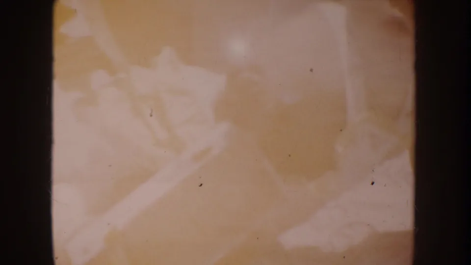 Warm amber 8mm frame from the 1962 Disneyland home movie, showing indistinct rounded forms through soft exposure.