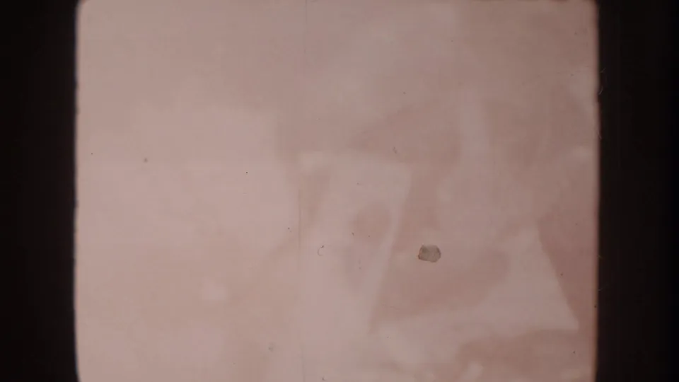 Faded pink 1962 Disneyland 8mm frame with a faint central shape, soft exposure, and visible dust specks.