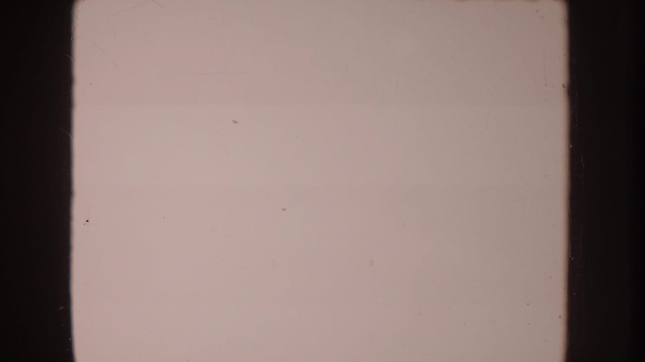 Mostly blank pale film frame with dark vertical borders and faint dust marks.