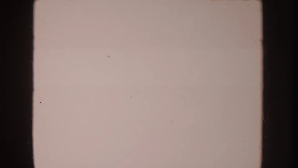 Faded 8mm frame from the supplied 1962 clip, showing a pale overexposed area with dark film borders and scattered dust.