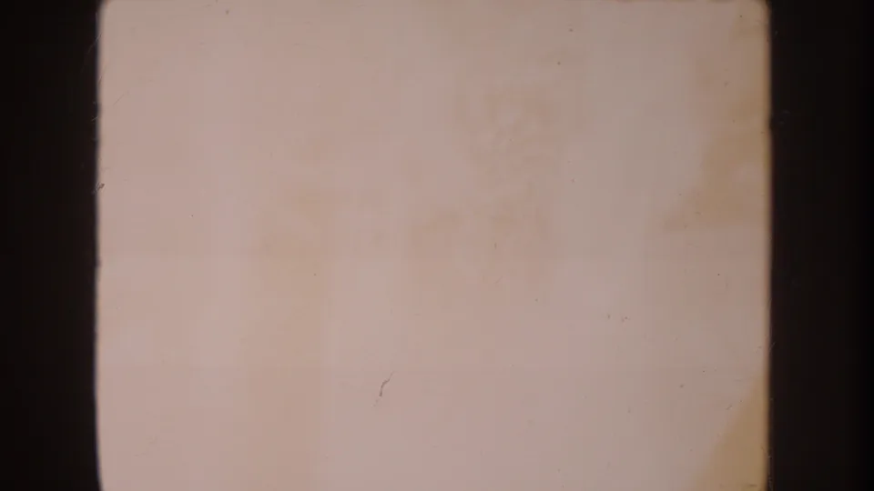 Faded 8mm frame from the same Disneyland home movie, mostly overexposed with only faint ground detail visible.