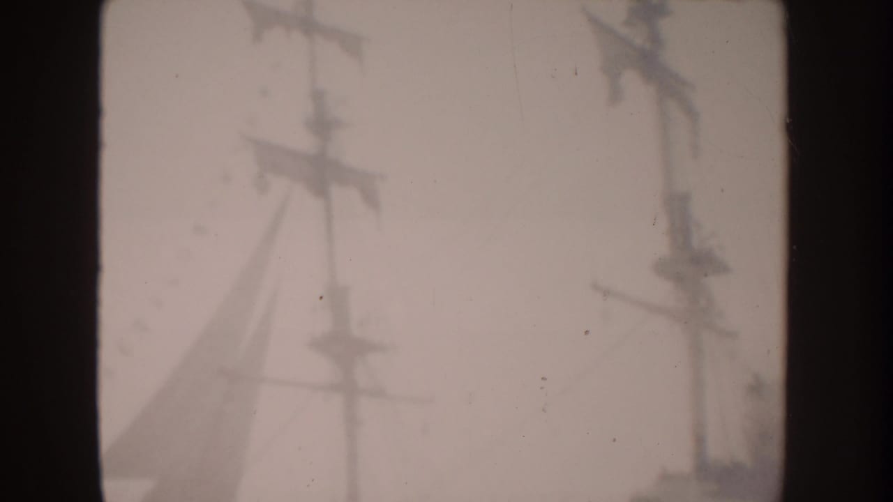 1962 Disneyland home-movie frame showing tall electric transmission poles and overhead wires through haze.