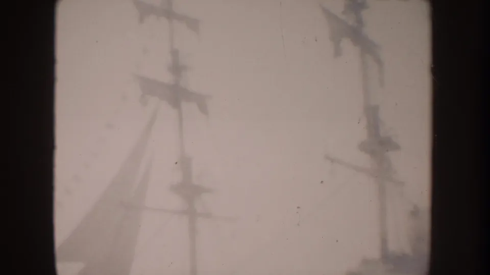 1962 Disneyland home-movie frame showing tall electric transmission poles and overhead wires through haze.