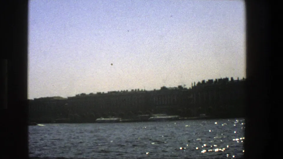 Final boat-view frame showing a pale sky, rippling lake water, and a shadowed Danish shoreline.