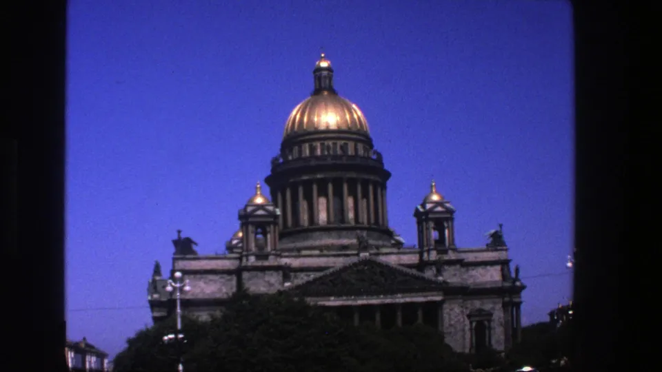 1975 8mm frame of the domed building seen slightly lower and closer, with trees obscuring part of the facade.