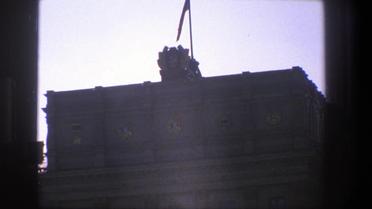 Dark framed view of a building roofline with a flag above the facade.