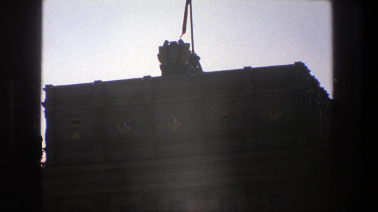 1975 Denmark 8mm frame showing a dark civic building silhouette with a flag and decorative facade details, viewed through heavy vertical framing.