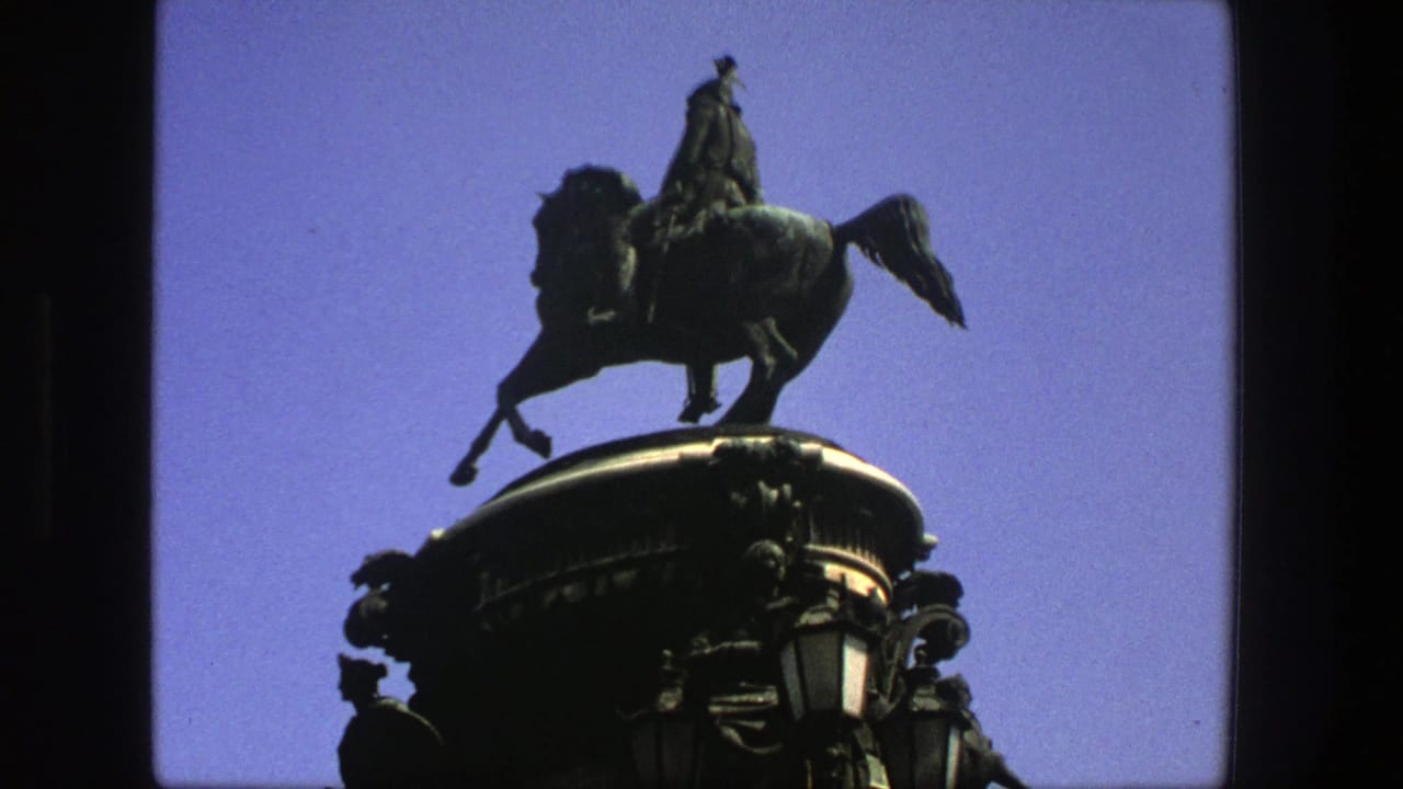 Equestrian statue and rounded pedestal photographed from below against blue sky.