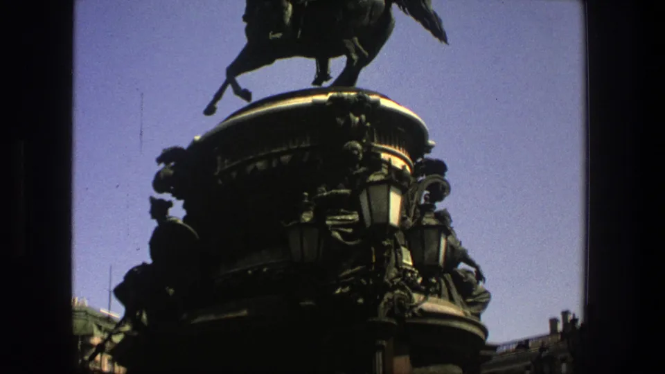 1975 Denmark 8mm frame showing the mounted rider statue and a dark, highly ornamented pedestal from a visitor's upward angle.