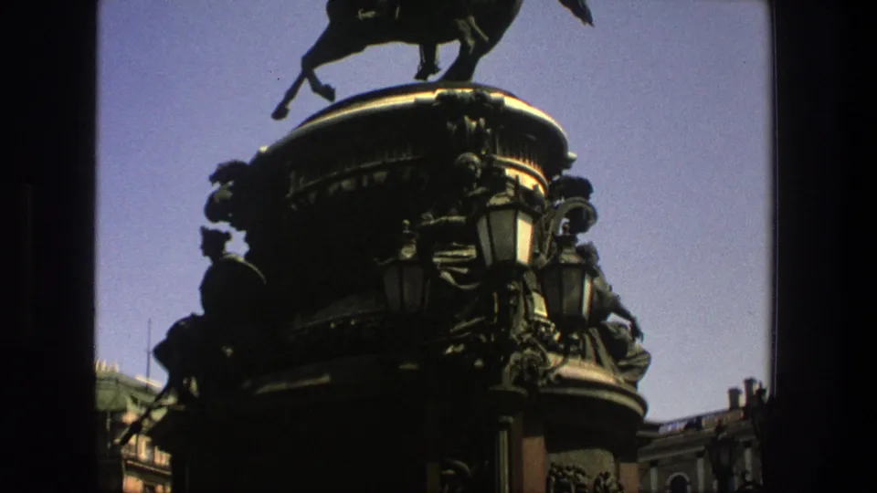 1975 8mm Denmark-labeled footage shows an ornate equestrian monument with a dark sculpted pedestal and street lamps.