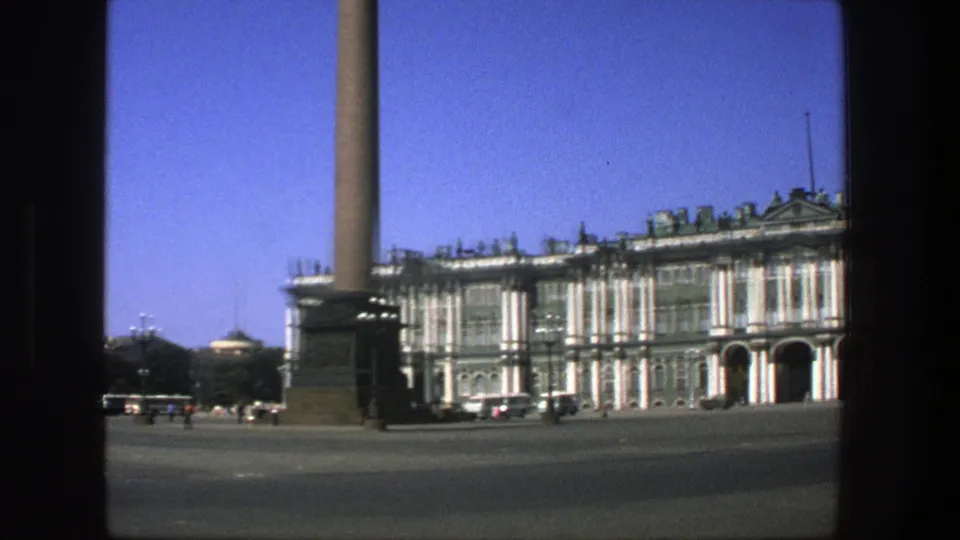 Wide 1975 8mm Denmark-labeled view of a public square, tall column, and classical building under a clear blue sky.