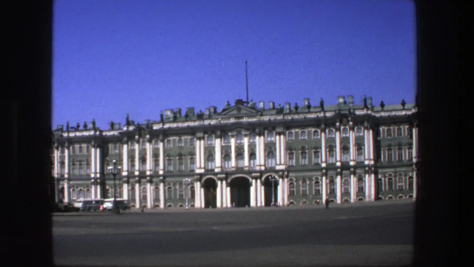 1975 Denmark 8mm frame of a grand green-and-white facade with columns, arched entrances, and small distant figures in the square.