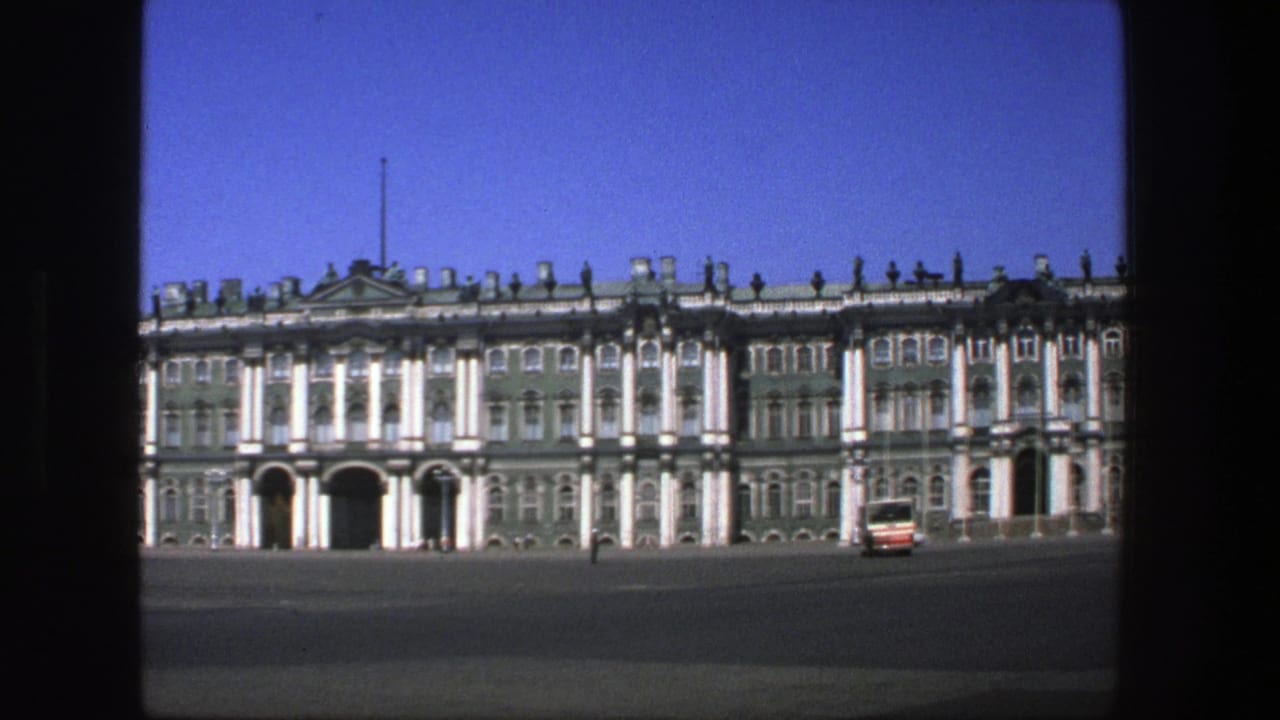 Historic palace-like facade with a red-and-white bus on the open square.