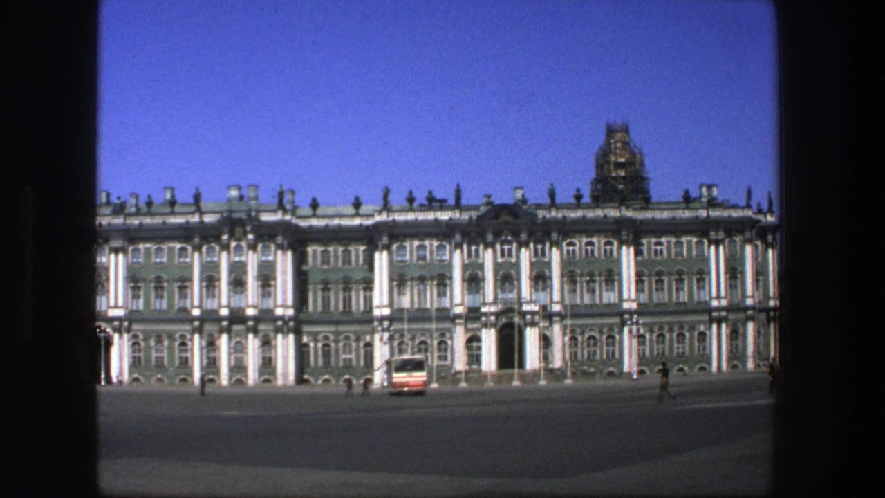 1975 8mm travel frame of a grand palace exterior in Denmark metadata, with a bus crossing the open plaza.