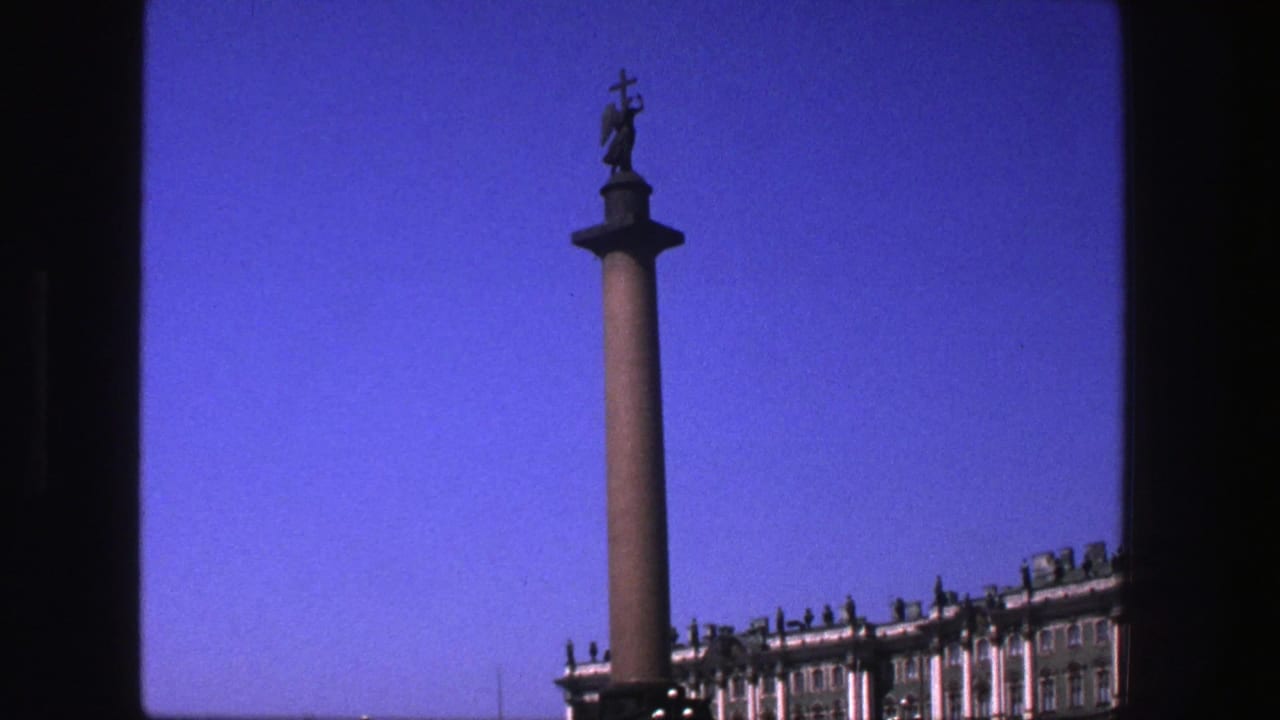 Angel-topped column and ornate building facade seen against a clear blue sky.