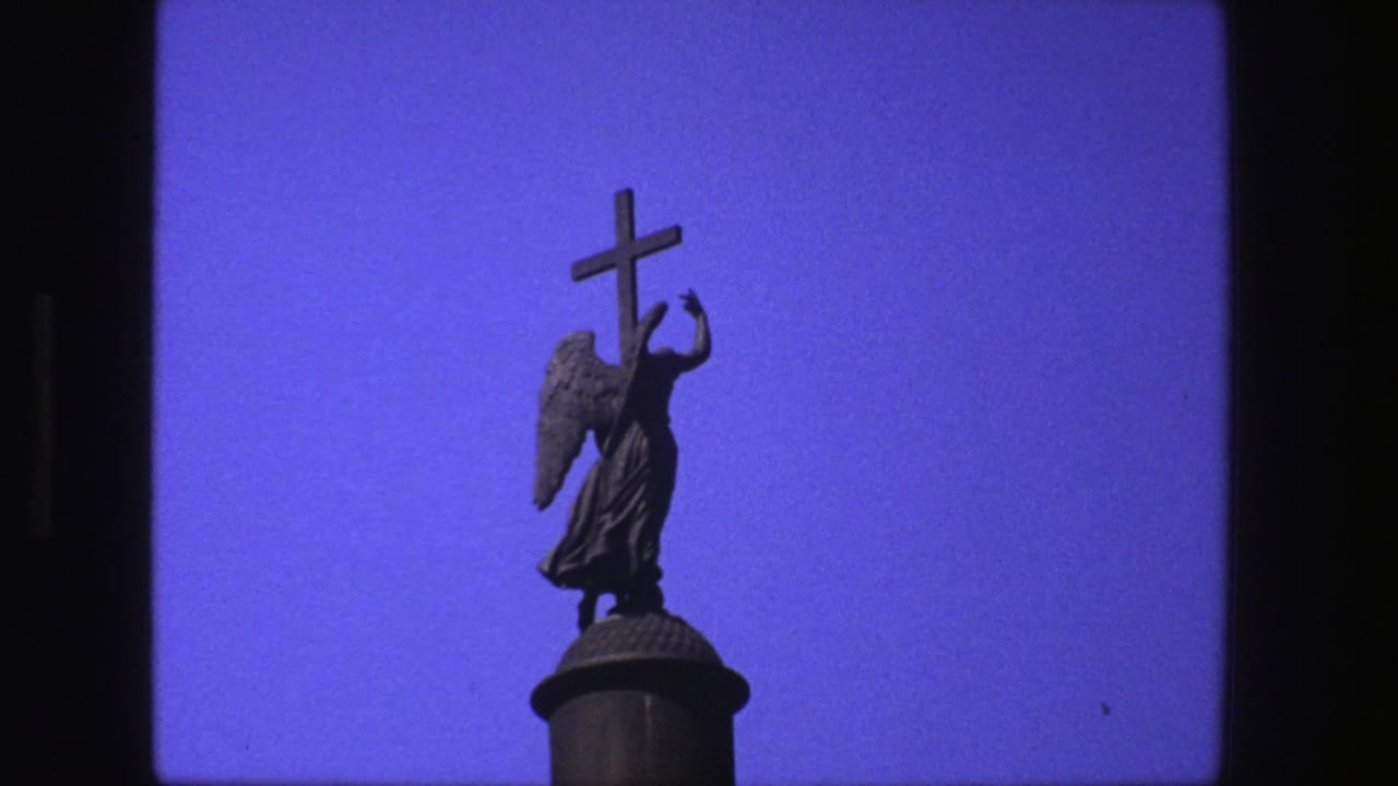 Angel statue holding a cross against a blue sky with dark film borders.