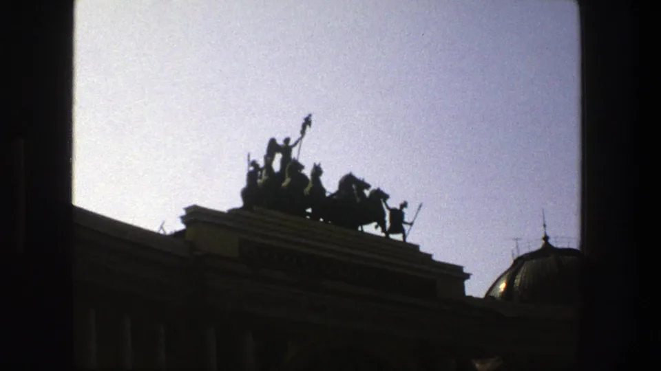 1975 Denmark 8mm frame showing a chariot and horses on a roofline, filmed from below with a dome at the right edge.