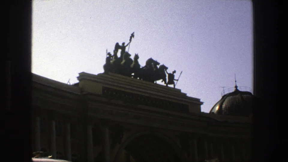 1975 Denmark 8mm frame showing silhouetted rooftop statuary, columns, and a domed roof detail in soft home-movie focus.
