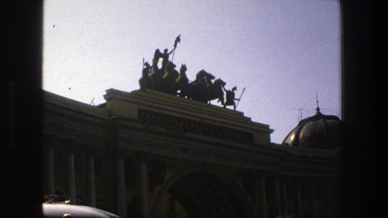 Classical building facade seen through a dark window frame with a rooftop statue group.