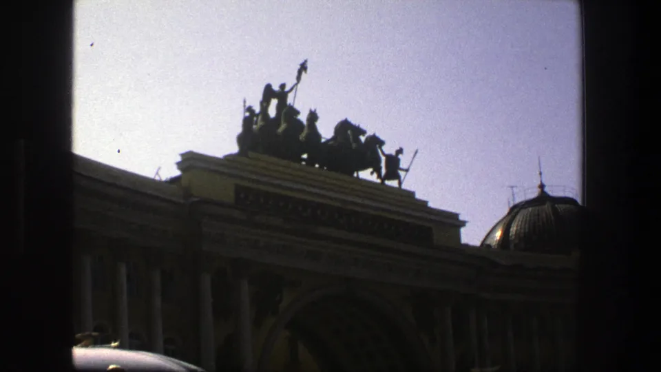 1975 Denmark 8mm frame showing a grand arched facade with columns and rooftop statuary, partially obscured by a dark window frame.
