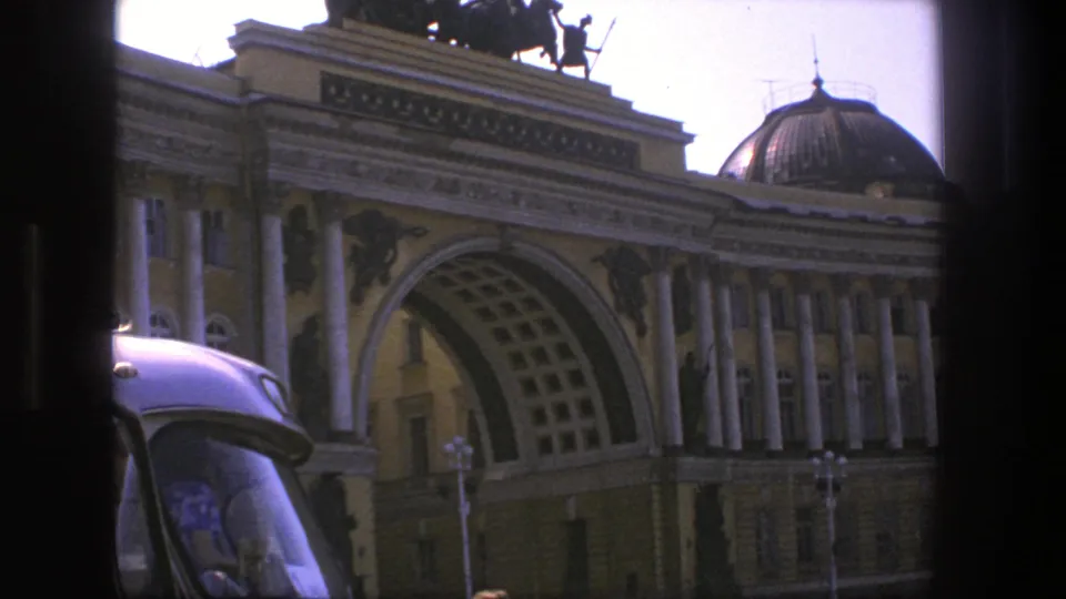 1975 Denmark 8mm still with a grand columned facade, large arch, domed roof, rooftop sculpture, and vintage car roof in front.