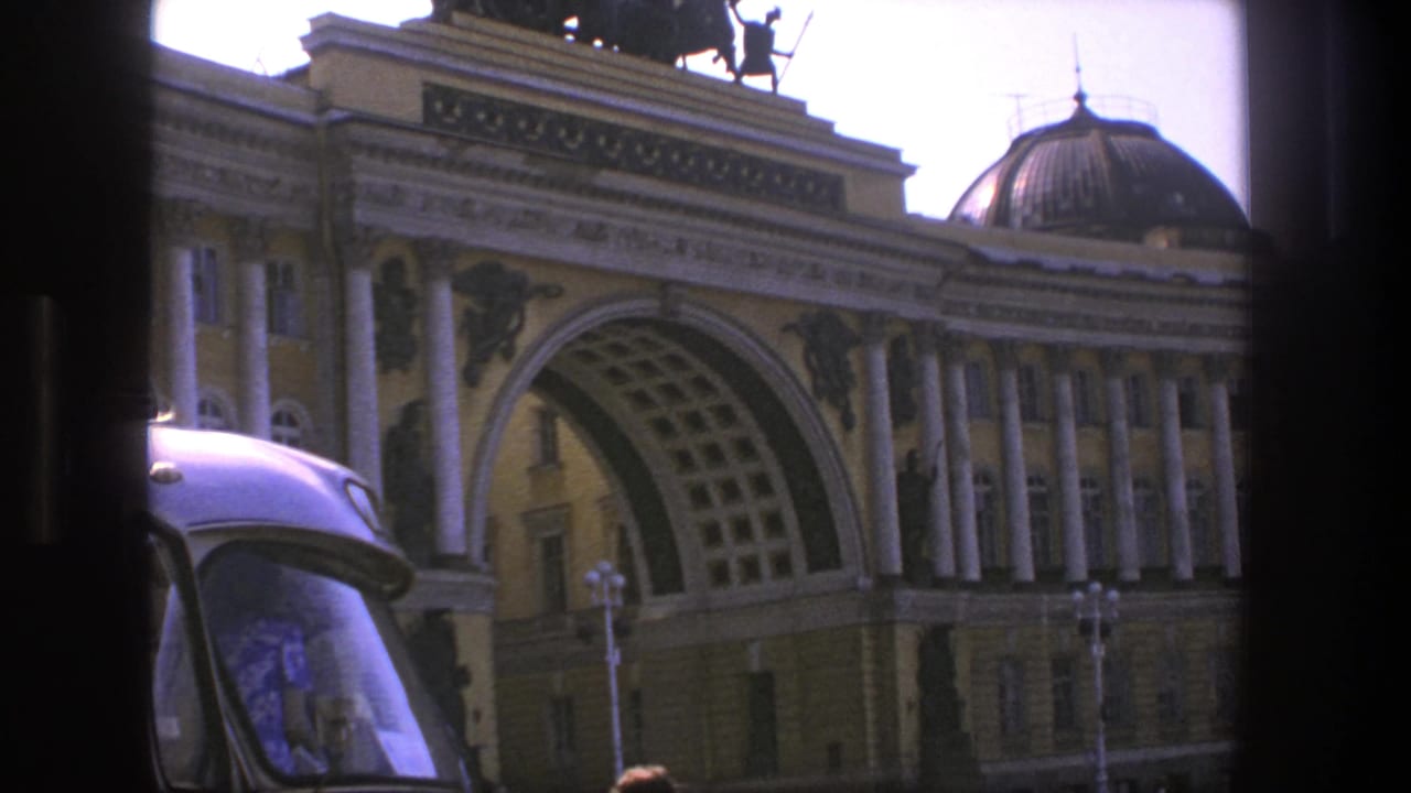 Classical arched building seen through dark bus window framing.
