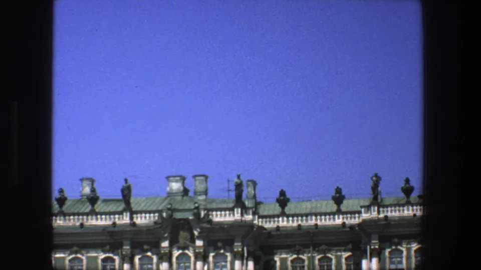 1975 Denmark frame showing an ornate roofline with statues, chimneys, and balustrade below a bright blue sky.