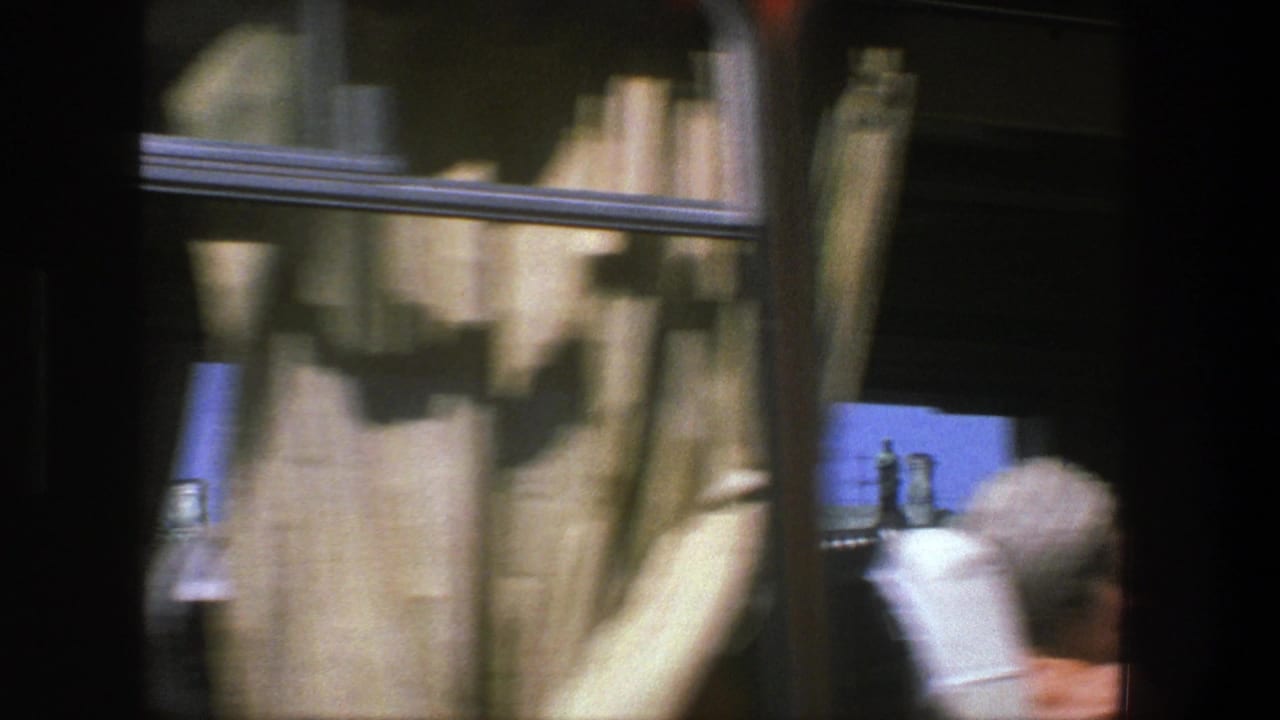 Construction sheeting passes close to the tram window with a partial figure at right.