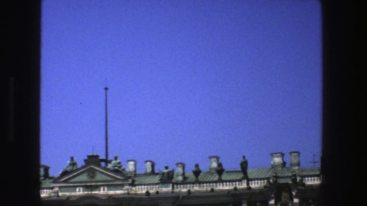 1975 Denmark home-movie frame showing ornate rooftop sculpture, chimneys, balustrade, and a flagpole across a historic building exterior.
