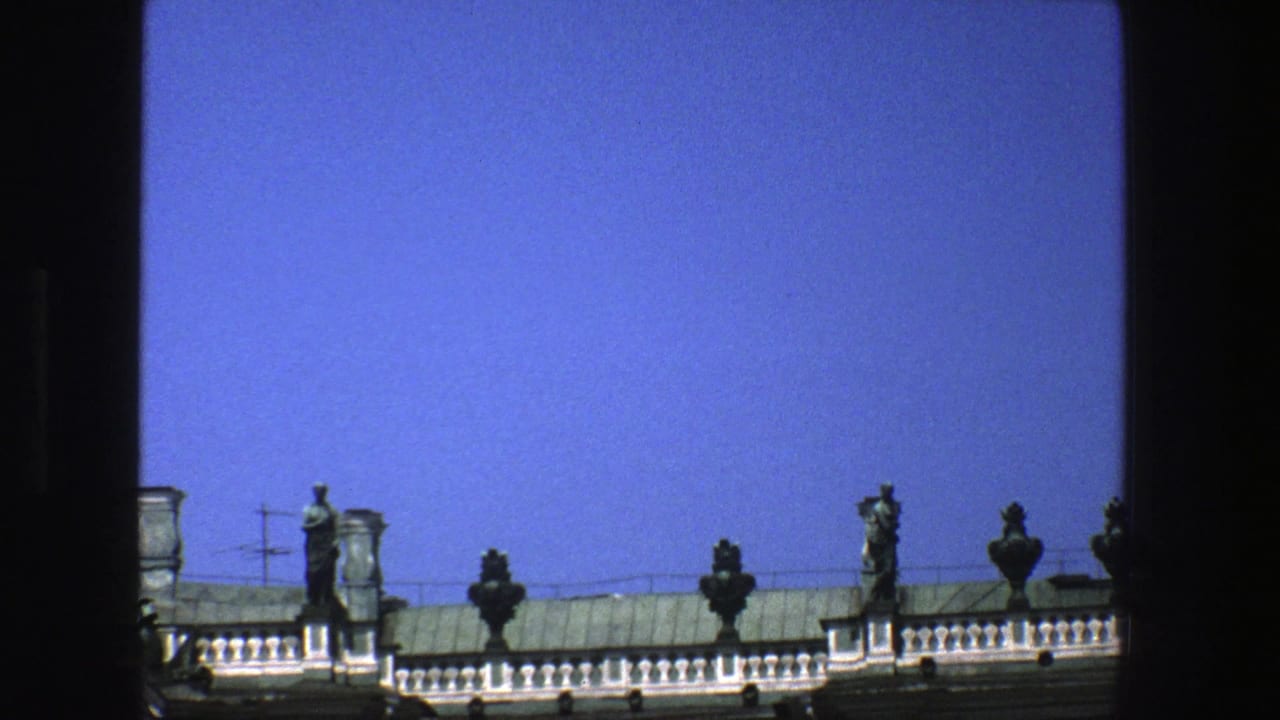 1975 Denmark travel footage frames green rooftop statuary and classical architectural details against a clear blue sky.