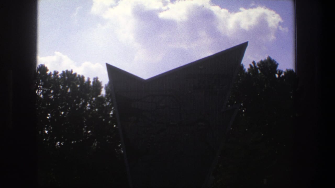 Angular landmark partly silhouetted with clouds and trees in the background.