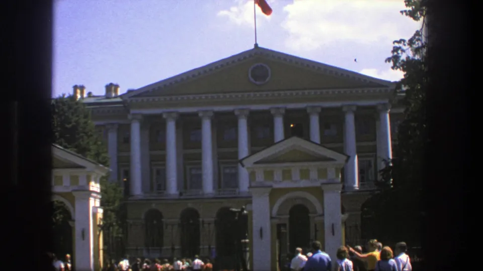 1975 Denmark 8mm frame of a grand columned building with a flag and visitors gathered near the entrance.