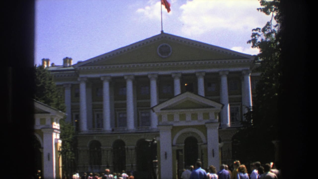 1975 Denmark 8mm frame showing a grand classical building with white columns, a flag above the roof, trees, and visitors gathered outside.