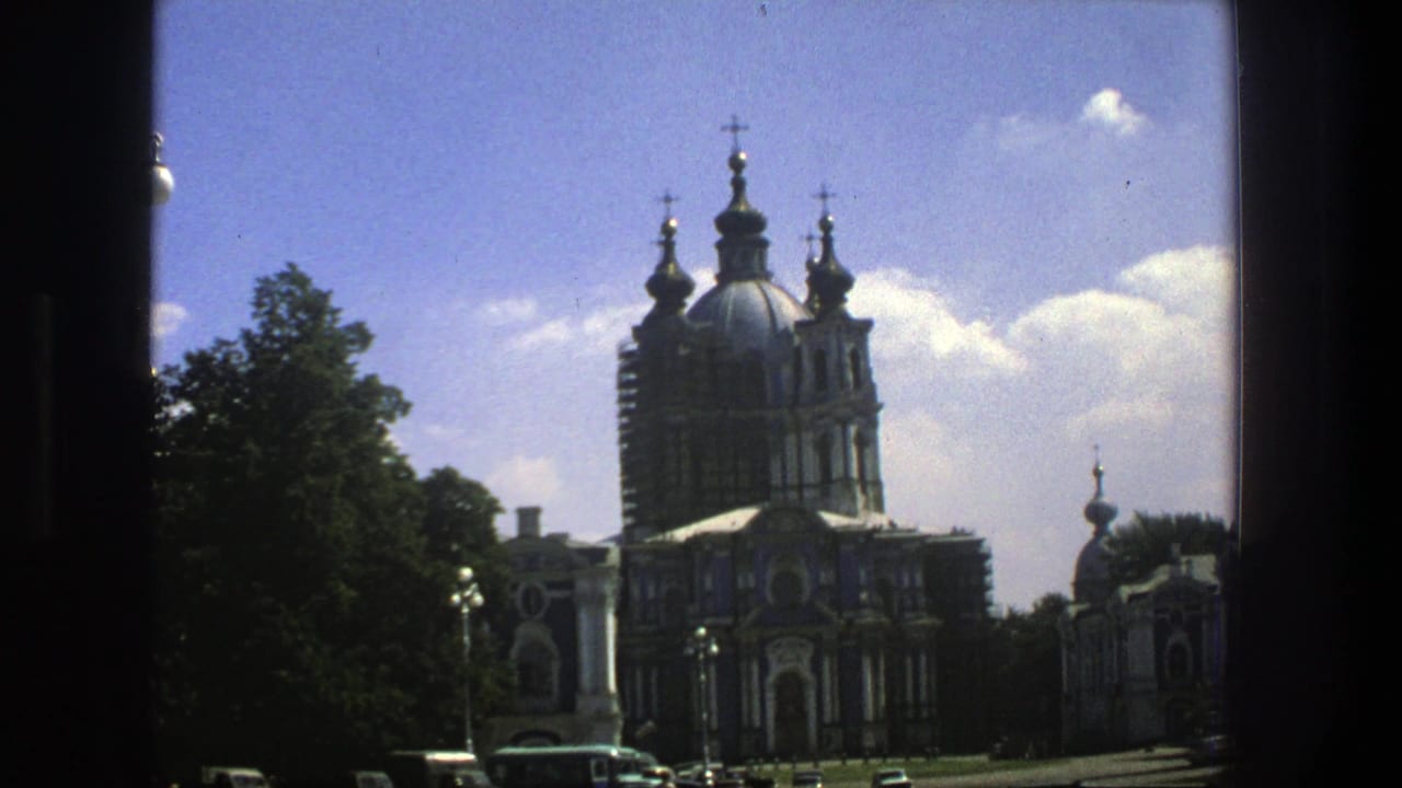 1975 8mm travel frame in Denmark showing an ornate domed church with crosses, trees, blue sky, and cars near the street.