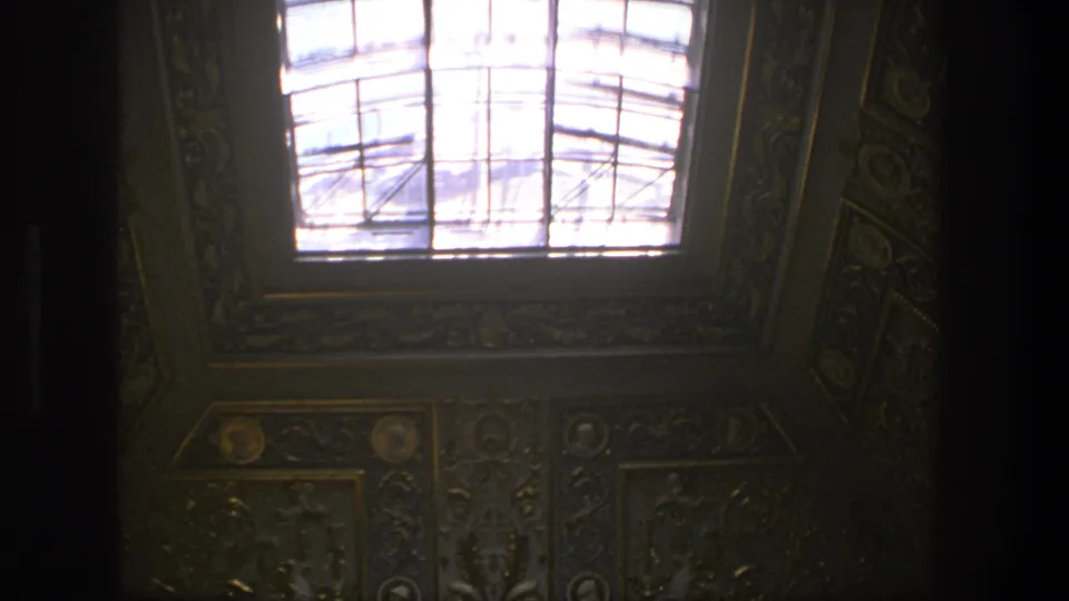 1975 Denmark 8mm view of a dim cathedral interior ceiling with ornate wall decoration and a bright rectangular skylight.