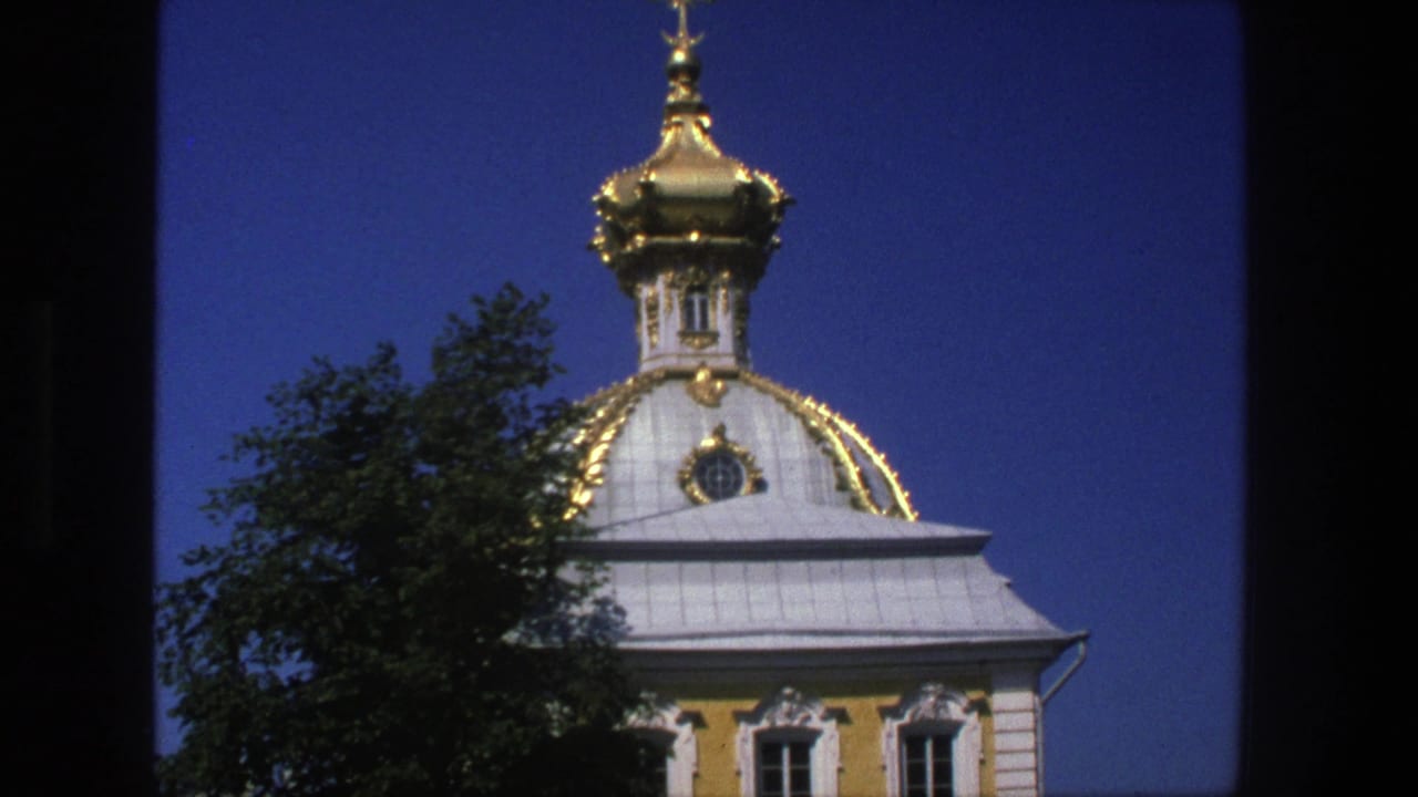 1975 Denmark 8mm frame showing an ornate golden church dome, cross finial, pale roof, yellow facade, and tree foliage.