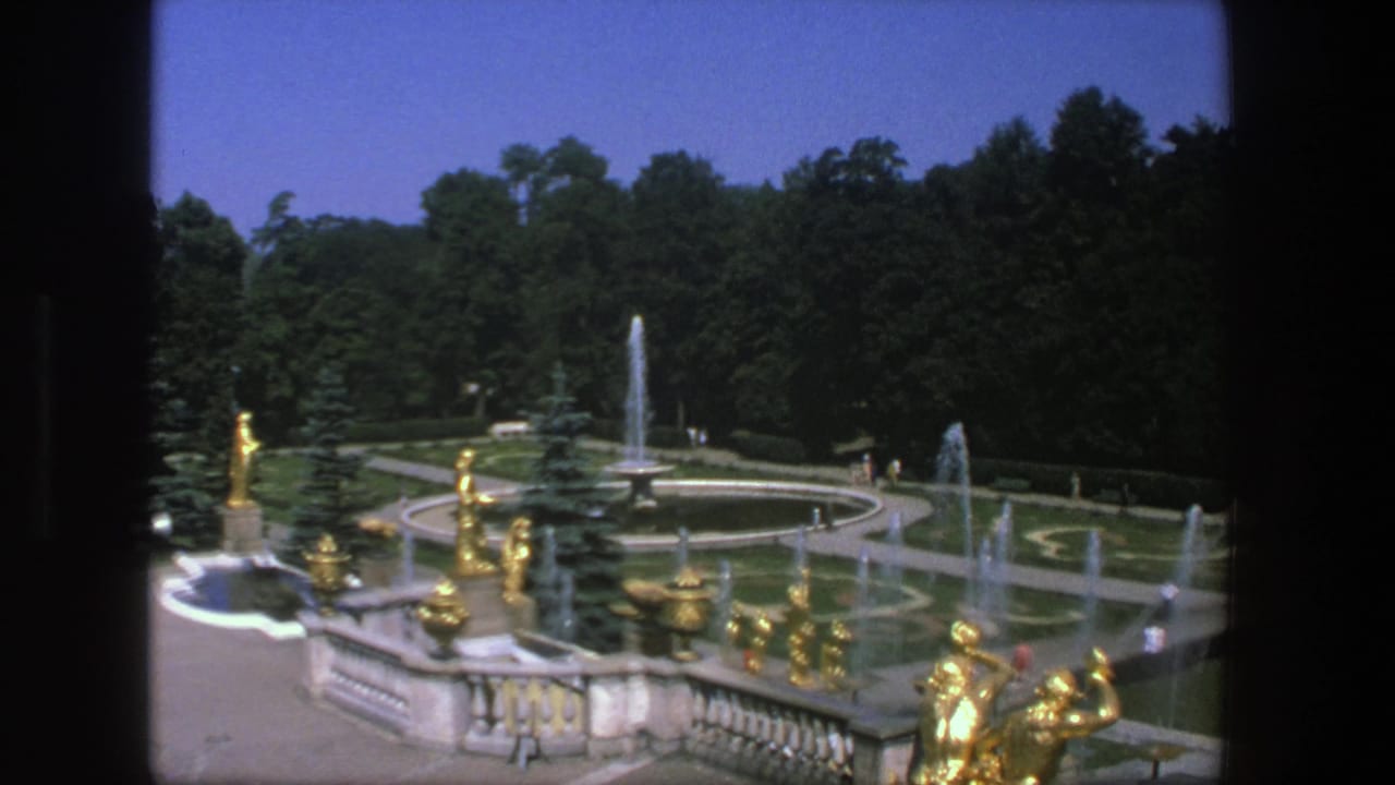 Denmark garden footage from 1975 showing gold-toned sculptures, fountain jets, curved walkways, trimmed lawns, and distant visitors.