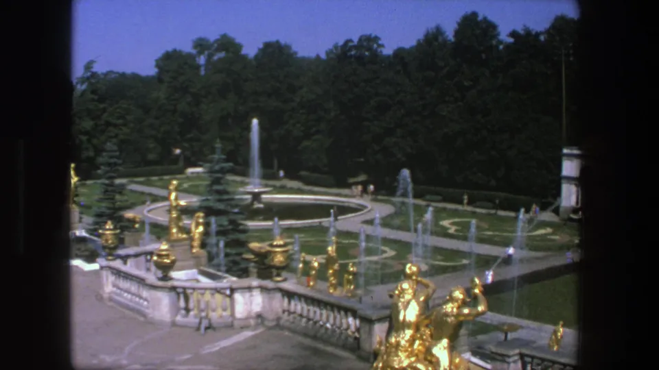 Elevated 1975 Denmark view across gilded garden figures, water jets, formal paths, manicured lawns, and dense trees.