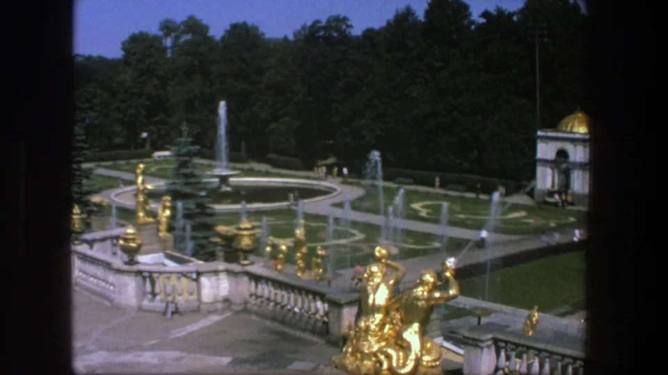 1975 Denmark garden overlook with gilded sculpture, multiple fountain sprays, formal paths, visitors, trees, and a small domed pavilion.